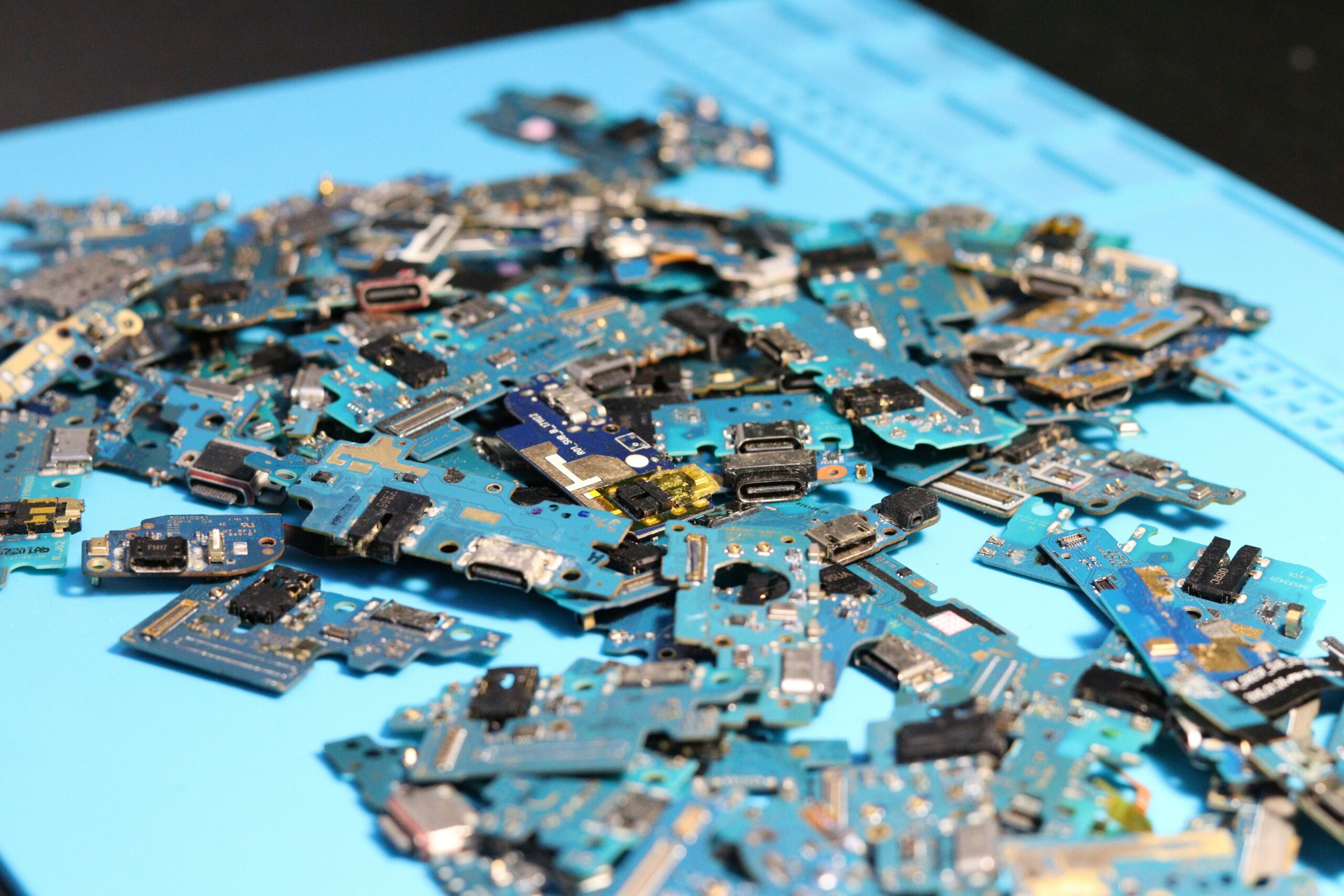 Several blue electronic circuit boards piled up on a blue mat
